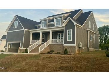 Charming two-story home featuring a welcoming front porch with white columns and a well-maintained lawn at 1221 Azalea Garden Cir, Raleigh, NC 27603