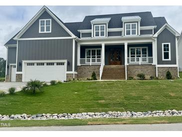 Charming two-story home with a covered front porch, well-manicured lawn, and a two-car garage at 1221 Azalea Garden Cir, Raleigh, NC 27603