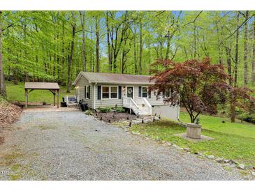Charming home featuring light gray siding, a welcoming front porch, and a gravel driveway surrounded by lush greenery at 1332 Stallings Rd, Chapel Hill, NC 27516