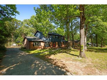 Charming two-story home with brick accents, blue siding, mature trees and a long concrete driveway at 204 N Gurney St, Burlington, NC 27215