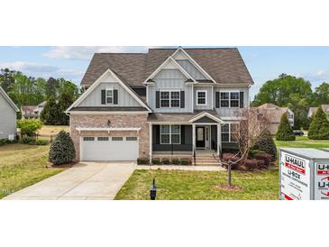 Charming two-story home featuring brick accents, gray siding, and a well-manicured lawn at 265 Beckwith Ave, Clayton, NC 27527