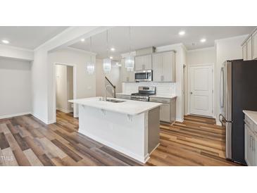 Modern kitchen features stainless steel appliances, gray cabinets, white subway tile backsplash, and island with sink at 272 Hiking Hill Ln, Garner, NC 27529