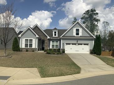 Charming single Gathering home featuring stone accents, a two-car garage, and meticulously manicured landscaping at 338 Apalachia Lake Dr, Fuquay Varina, NC 27526