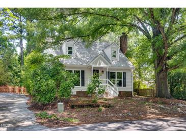 Charming home featuring dormer windows, white siding, mature trees, and a cozy front porch at 3421 E Jameson Rd, Raleigh, NC 27604