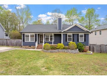 Charming blue home with a well-manicured lawn and inviting front yard landscaping at 408 Teal Lake Dr, Holly Springs, NC 27540