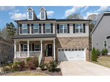 Charming two-story home features a brick and siding exterior, dormer windows, and a welcoming front porch at 420 Cahors Trl, Holly Springs, NC 27540