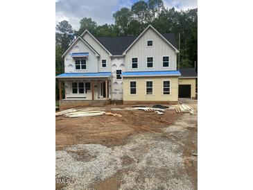 Two-story home with a dark roof, light siding, and visible construction materials in the yard at 70 Valebrook Ct, Youngsville, NC 27596