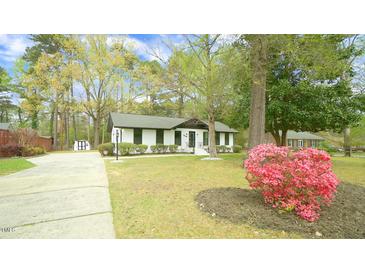 Charming single-story home featuring a well-manicured lawn and blooming azalea bushes at 909 Windcrest Rd, Durham, NC 27713