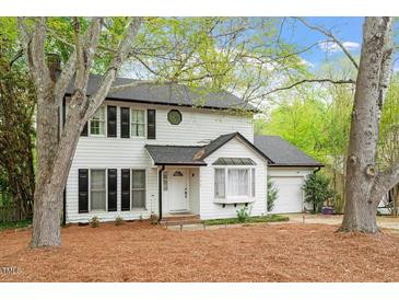 Charming two-story home featuring white siding, black shutters, and mature trees in a well-maintained landscape at 1003 Buckhorn Rd, Garner, NC 27529