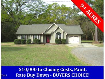 Charming single-story home with a well-manicured lawn and attached garage on over 9 acres at 126 Creedmoor Rd, Stem, NC 27581