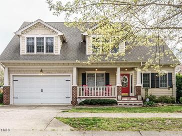 Charming home featuring a welcoming front porch, manicured lawn, and an attached two-car garage at 1625 Heritage Garden St, Wake Forest, NC 27587