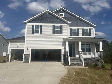 Two-story home featuring a two-car garage, porch, gray siding, and dark shutters set against a bright blue sky at 176 Golfview Ave, Benson, NC 27504