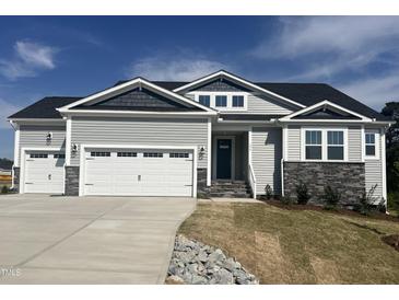 Charming home featuring a three-car garage, stone accents, and attractive gray siding under a blue sky at 196 Golfview Ave, Benson, NC 27504