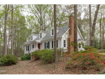 Charming two-story home with white siding, black shutters, red door, and mature landscaping at 2629 Sweetgum Dr, Apex, NC 27539