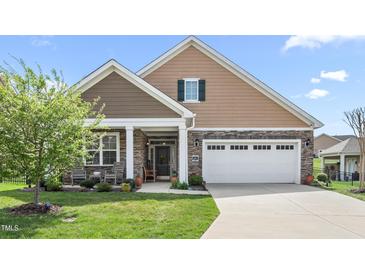 Charming home featuring a two-car garage, stone accents, covered entryway, and manicured lawn at 667 Ashley Woods Dr, Gibsonville, NC 27249