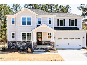 Charming two-story home with stone accents, attached garage, and landscaped front yard at 68 Tee Time Ter, Benson, NC 27504