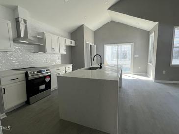 Bright kitchen featuring white cabinetry, stainless steel appliances, and a large center island with a black faucet at 825 Long Ave, Rocky Mount, NC 27801