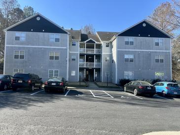 Three story condo building with covered entrance, multiple balconies, and ample parking space on a sunny day at 1140 Carlton Ave # 201, Raleigh, NC 27606