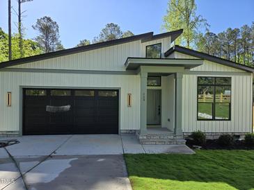 Charming home with black garage door, modern architectural features, and well-manicured lawn at 124 Horseman Dr, Louisburg, NC 27549