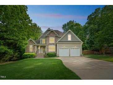 Charming two-story home with stone accents, well-manicured lawn, mature trees and a two car garage at 1404 Rhea Dr, Garner, NC 27529