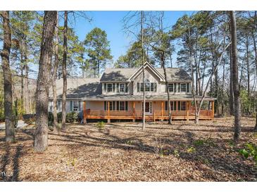 Charming two-story home featuring a welcoming front porch and surrounded by mature trees at 167 Coachmans Cove Rd, Four Oaks, NC 27524