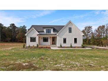Charming white farmhouse with black trim, stone accents, and a well-manicured lawn, under a sunny blue sky at 1886 Mays Crossroad Rd, Louisburg, NC 27549
