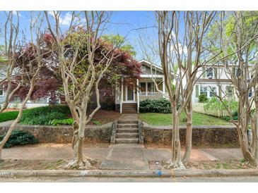 Charming home exterior featuring a welcoming porch, stone wall, and mature landscaping at 306 Perry St, Raleigh, NC 27608