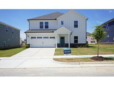 Charming two-story home featuring a two-car garage, teal front door, and a well-manicured lawn at 3409 Rosebush Dr, Zebulon, NC 27597