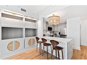 Bright kitchen with white cabinets, stainless appliances, island with white countertop and decorative chandelier at 510 Glenwood Ave # 602, Raleigh, NC 27603