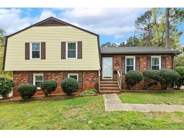 Traditional two-story home featuring a brick facade and vinyl siding, complimented by a well-maintained lawn and landscaping at 5401 Kaplan Dr, Raleigh, NC 27606