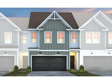 Charming two-story townhome with a dark garage door, craftsman details, and a well-manicured lawn at 6023 Enclosure Way, Durham, NC 27703
