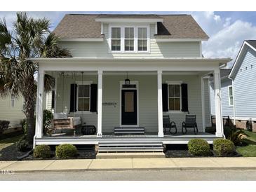 Charming two-story home with a welcoming front porch, swing, and lush landscaping at 65 Oglethorpe Ave, Clayton, NC 27527