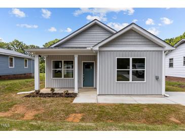 Charming gray home with welcoming front porch, complemented by tidy landscaping and bright white trim at 815 Goshen St, Oxford, NC 27565