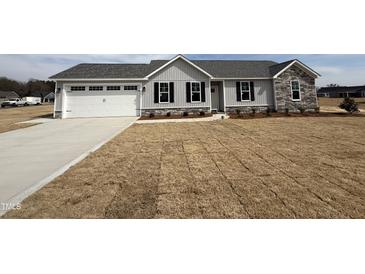 Charming single-story home with gray siding, stone accents, and an attached two-car garage at 102 Ruskin Dr, Smithfield, NC 27577