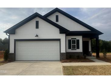 New construction home with a white façade, black trim, and a two-car garage at 11778 Salers Loop, Middlesex, NC 27557