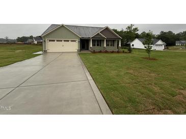 Charming one-story home with a two-car garage and well-manicured lawn on a cloudy day at 141 Ruskin Dr, Smithfield, NC 27577