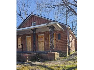 Red brick home with covered front porch, boarded up windows and overgrown landscaping at 1421 Blanton St, Rocky Mount, NC 27803