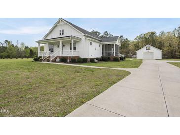Charming two-story white farmhouse-style home with a welcoming front porch and manicured landscaping at 184 Mort Harris Rd, Louisburg, NC 27549