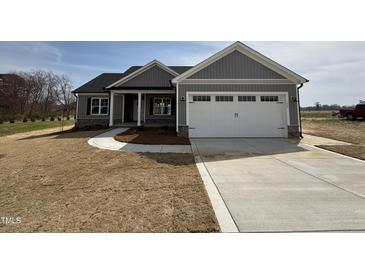 Charming single-story home with a two-car garage, covered porch, and newly installed gray siding at 32 Tanseyleaf Dr, Smithfield, NC 27577