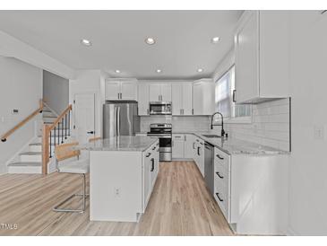 Bright kitchen features white cabinets, stainless steel appliances, and granite countertops at 5430 Crabtree Park Ct, Raleigh, NC 27612