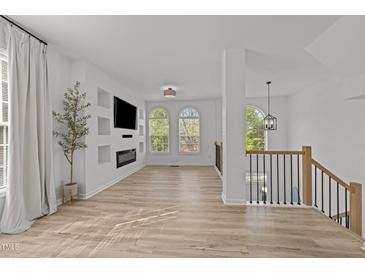 Bright living room features hardwood floors, fireplace, built-in shelving, and arched windows at 5430 Crabtree Park Ct, Raleigh, NC 27612