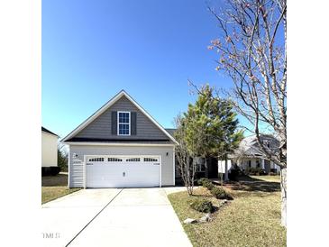 Charming home with a two-car garage, gray siding, and a manicured lawn on a bright, sunny day at 6320 Slopeside Ct, Raleigh, NC 27610