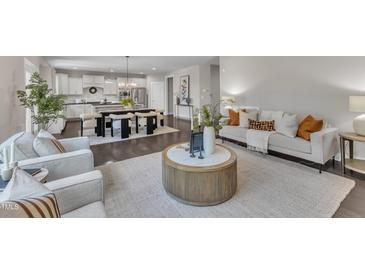 Open concept living room showcasing modern furnishings, hardwood floors, and a view to the kitchen and dining area at 706 Fireball Ct, Knightdale, NC 27545