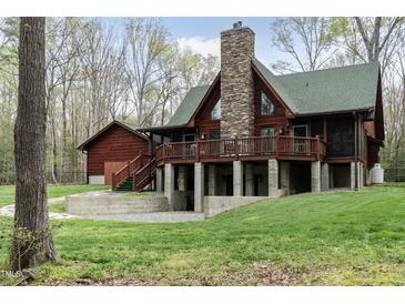 Secluded log home with stone chimney, basement access, and covered porch overlooking a lush lawn at 932 Gynnis Creek Dr, Moncure, NC 27559