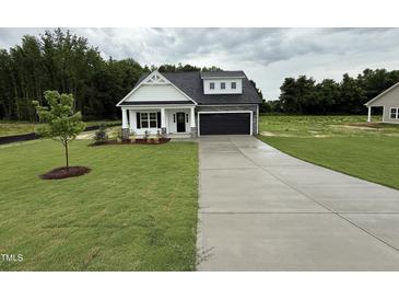 Charming single-Gathering home featuring a well-manicured lawn and a two-car garage, complete with a modern black door at 105 Tuskeegee Dr, Smithfield, NC 27577