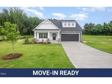 Charming home with white siding, stone accents, black garage doors, and a well-manicured lawn at 105 Tuskeegee Dr, Smithfield, NC 27577