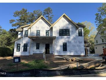Two story home under construction, featuring black windows, Tyvek wrap, and a covered front porch at 1116 Kimberly Dr, Raleigh, NC 27609