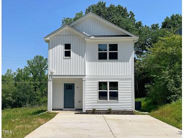 Charming two-story home with white siding, a blue front door, and a concrete driveway at 112 Remington Woods Dr, Wake Forest, NC 27587