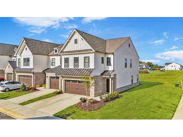 Beautiful townhome with white siding, brick accents, and a two-car garage, complemented by a well-manicured lawn at 125 Paperwhite Pl, Clayton, NC 27527