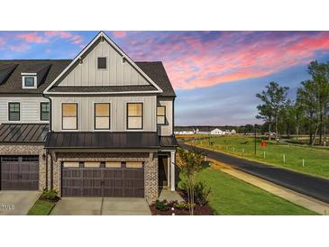 Beautiful two-story townhome showcasing a brick and gray facade with a two car garage and attractive landscaping at 125 Paperwhite Pl, Clayton, NC 27527